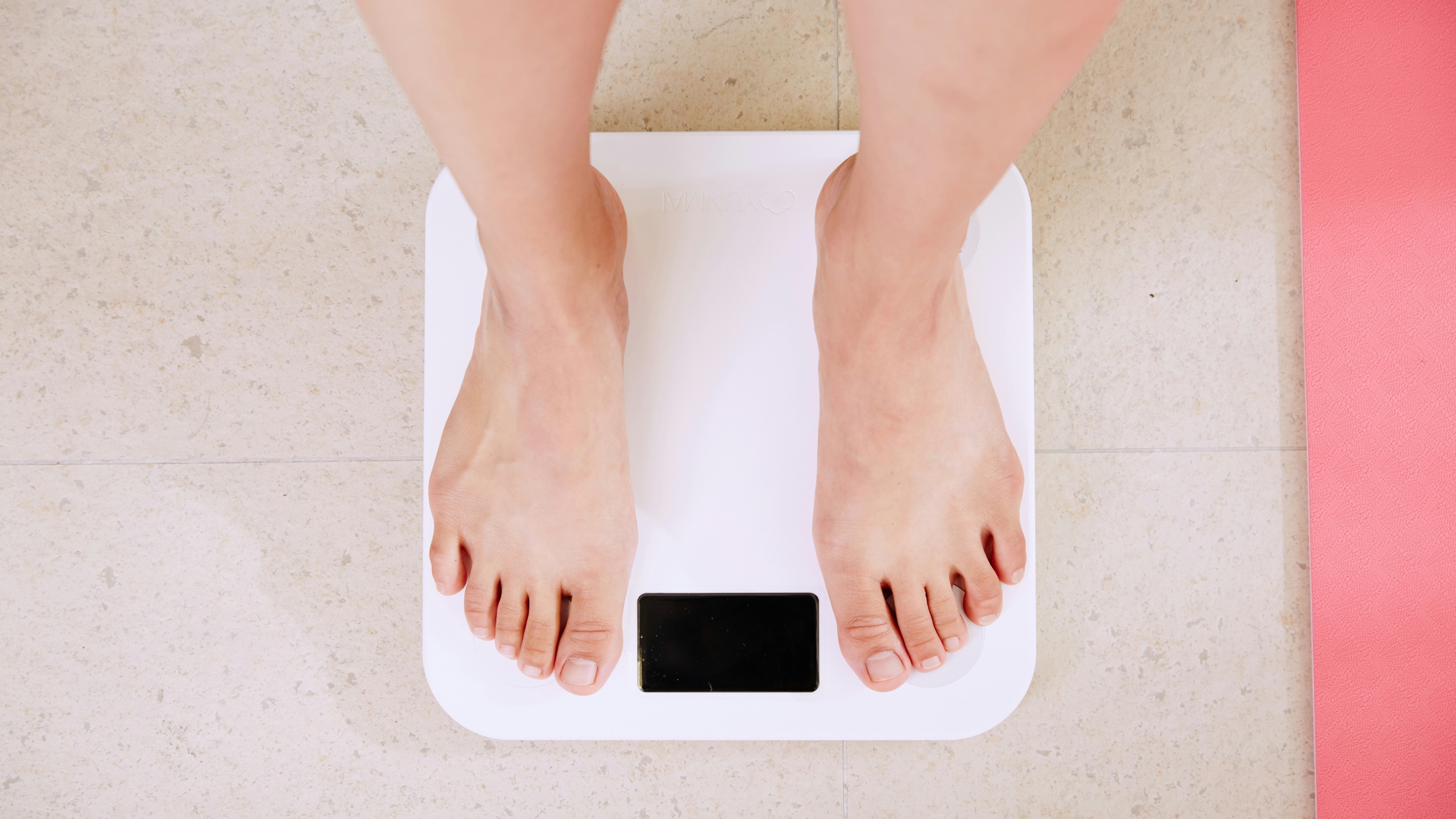 A person standing barefoot on a white digital bathroom scale viewed from above